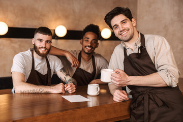 Wall Mural - Three cheerful men baristas at the coffee shop