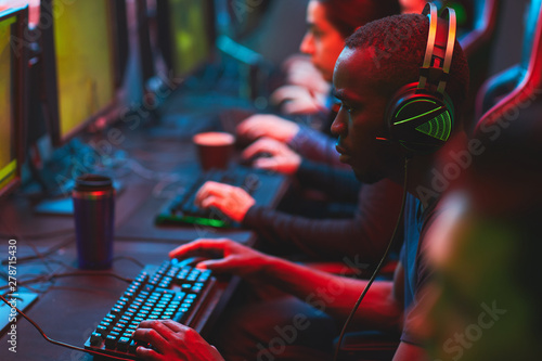 Fotografía Group of serious focused multi-ethnic gamers sitting in row and playing video ga
