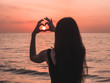 girl in a dawn makes a heart with her hands
