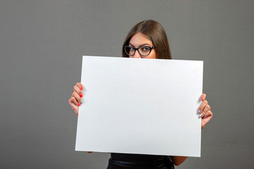 Beautiful woman holding a blank billboard isolated on gray background - image