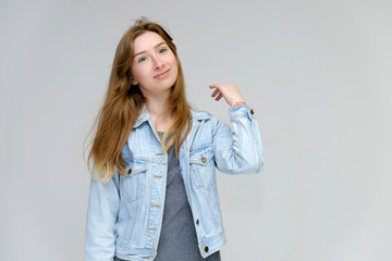 Portrait to waist of a young pretty brunette girl woman with beautiful long hair on a white background in a jacket from jeans. He talks, smiles, shows his hands with emotions in various poses.