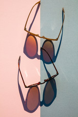 Poster - Fasionable summer sunglasses with long shadow on pink and blue background