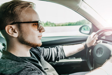 Wall Mural - European male driver businessman driving a car on a sunny trip.