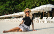 © Artem Markin - A girl in a straw hat sits on the morning beach. Modern girl on vacation