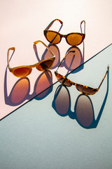 Poster - Fasionable summer sunglasses with long shadow on pink and blue background