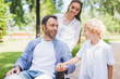 © LIGHTFIELD STUDIOS - mother and adorable son with disabled father on wheelchair in park during daytime