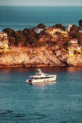 Wall Mural - Luxury motor yacht at anchor of a cliff with villas and sunset summer warm light with blue ocean water. Port d' Andratx, Port Andratx, Mallorca Spain Balearics