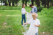 © LIGHTFIELD STUDIOS - family picking up garbage in plastic bags in park with copy space
