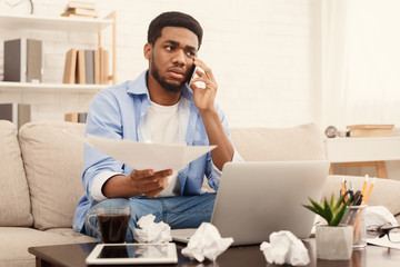 Serious man holding paper and talking on mobile phone