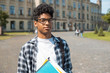 © Oleksandr - Smiling African American student in glasses with books. Happy mixed race guy near college.