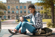 © Oleksandr - A black African American student in glasses with books sits near a college.