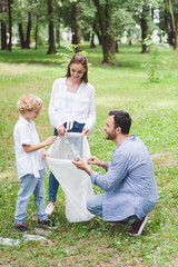 Wall Mural - happy family picking up garbage in plastic bag in park