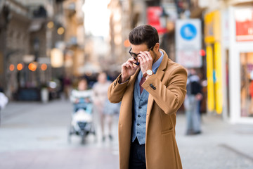 an elegant man walking and talking on his phone
