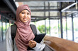 close up young beautiful malaysian student woman smiling and holding tablet at school buildings outside for study abroad concept