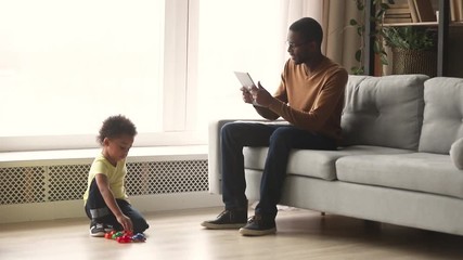 Wall Mural - African father and kid son spend time in living room