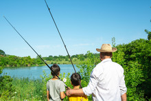 Two Boys And Grandfathers Went Fishing.  They Stand On The Shore Of The Pond And Look Into The Distance.