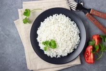 Steamed Rice On Black Plate. Gray Stone Background. Top View.