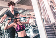 © junce11 - Woman is working out in fitness machine with male trainer is helping her in the back
