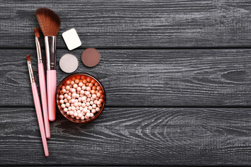 Brushes with makeup cosmetics on black wooden table