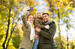 © Syda Productions - family, leisure and people concept - happy mother, father and little daughter taking selfie by smartphone over autumn park background