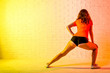 © mihakonceptcorn - Young athletic woman doing lunges on a yellow background.