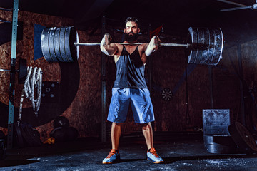 Wall Mural - Muscular bearded tattoed fitness man doing deadlift a barbell over his head in modern fitness center. Functional training. Snatch exercise