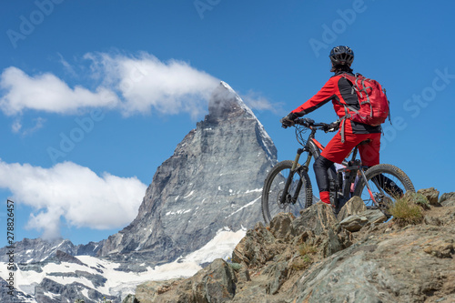 active senior woman, riding her electric mountainbike below the famous Matterhor Fototapete