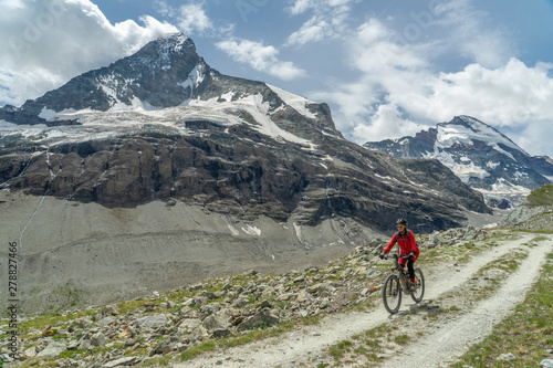 active senior woman, riding her electric mountainbike below the famous Matterhor Fototapete