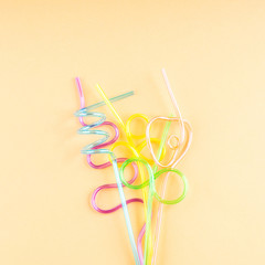 Wall Mural - Colorful funny shape party cocktail straws on orange. Flat lay with copy space