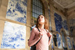 © Westend61 - Young woman with backpack standing in front of station building looking around, Porto, Portugal