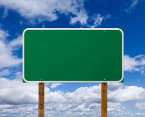 Wall Mural - Blank Green Road Sign with Wooden Posts Over Blue Sky and Clouds
