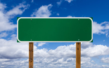 Wall Mural - Blank Green Road Sign with Wooden Posts Over Blue Sky and Clouds