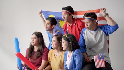 Wall Mural - excited asian young supporter holding malaysia flag over white background