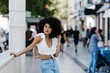 © Alexandra Coelho/ADDICTIVE STOCK - Young African American woman in jeans and crop top relaxing leaning on stone railing and looking at camera outdoors