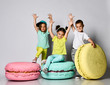 © FAB.1 - Three friends of triplets - two girls and a boy in bright clothes have fun at the birthday party fun room decoration candy macarons