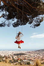 Girl Having Fun With Red Skirt And Hat Swinging While Contemplating The City In The Background