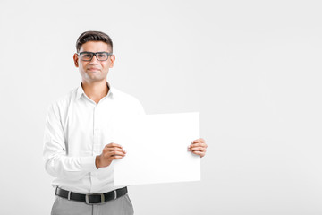 Young Indian business executive showing blank sign board over white background