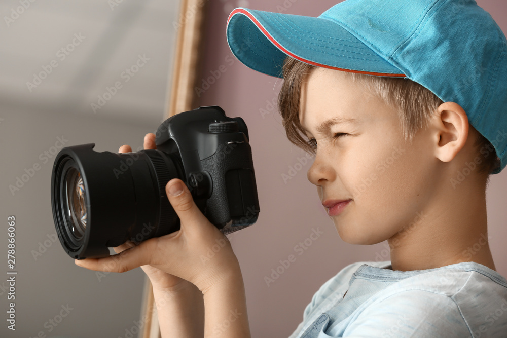 Cute little photographer with professional camera at home