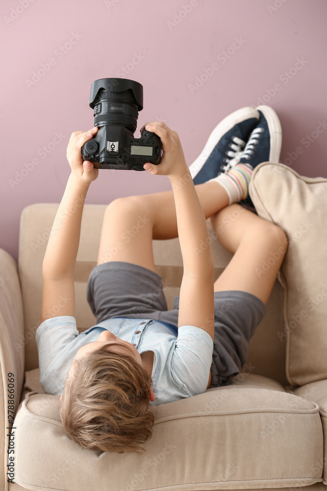 Cute little photographer with professional camera at home