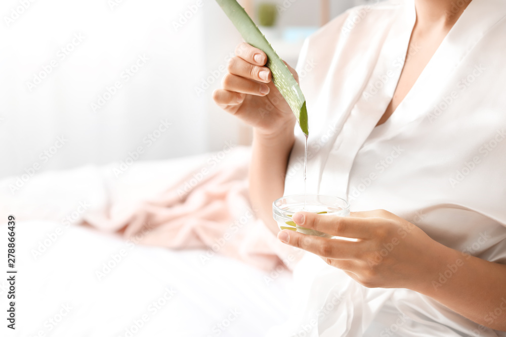 Beautiful young woman using aloe vera at home, closeup