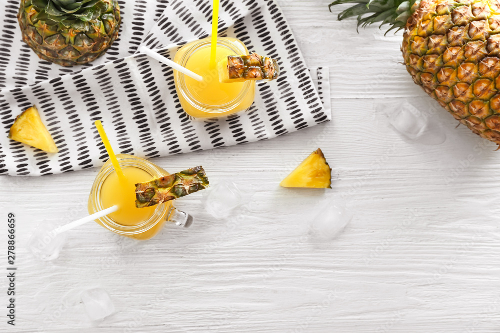 Mason jars of tasty pineapple juice on white table