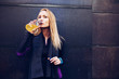© Ramon Lopez/ADDICTIVE STOCK - Young blonde caucasian woman drinking isotonic drink while having a rest from a running session leaning in a wall