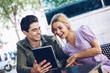 © Ramon Lopez/ADDICTIVE STOCK - Cheerful young attractive couple using tablet outdoors in town in warm day