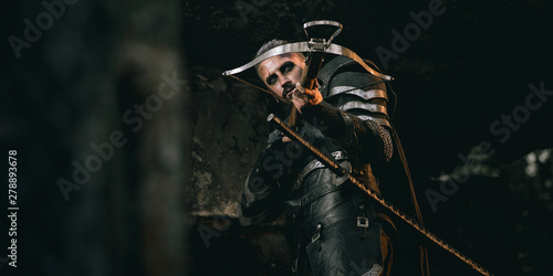 Mystery scarface knight in armor with sword and crossbow in the forest Tableau sur Toile