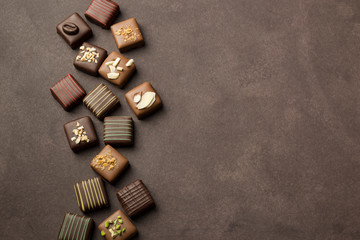 Wall Mural - chocolates praline variety on brown background with copyspace