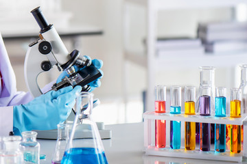 Canvas Print - Scientist using microscope in laboratory with lab glassware containing chemical liquid, science or medical research and development concept 