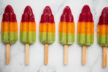 Wall Mural - Summer fruit ice lolly popcicle on a marble background