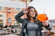 © Look! - Glad white woman posing with eyes closed holding glass of orange cocktail. Outdoor portrait of funny curly girl in tweed jacket relaxing in restaurant in autumn day.