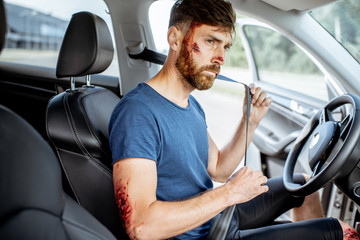 Wall Mural - Fastened driver with deep bleeding injuries after the road accident inside the car, feeling safe with security belt