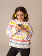 © SB Arts Media - Pretty young teenager girl in headphones listening to music on mobile phone isolated on grey